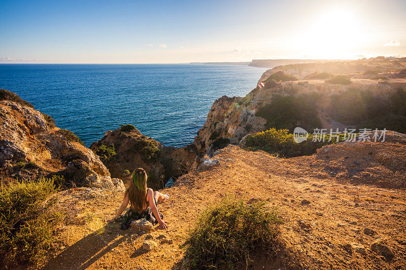 在葡萄牙阿尔加维的Ponta da Piedade悬崖边看日落的女人